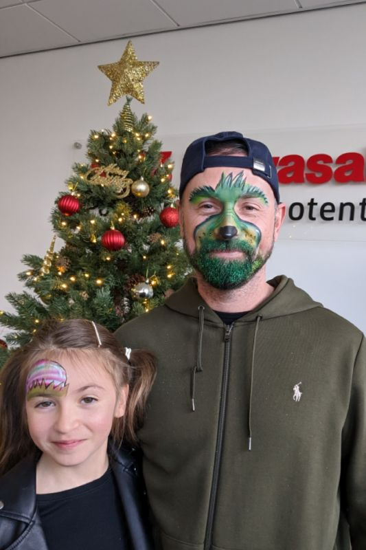 Grinch and daughter with glitter beard using fine green glitter daughter has an elf hat above eyebrow